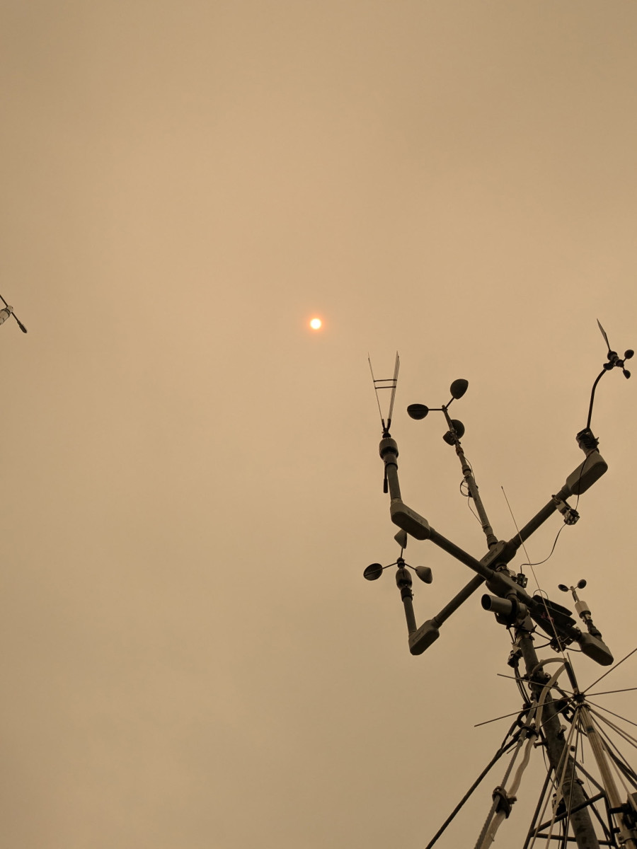 The Observatory's instrument mast silhouetted against a hazy orange sky thick with wildfire smoke