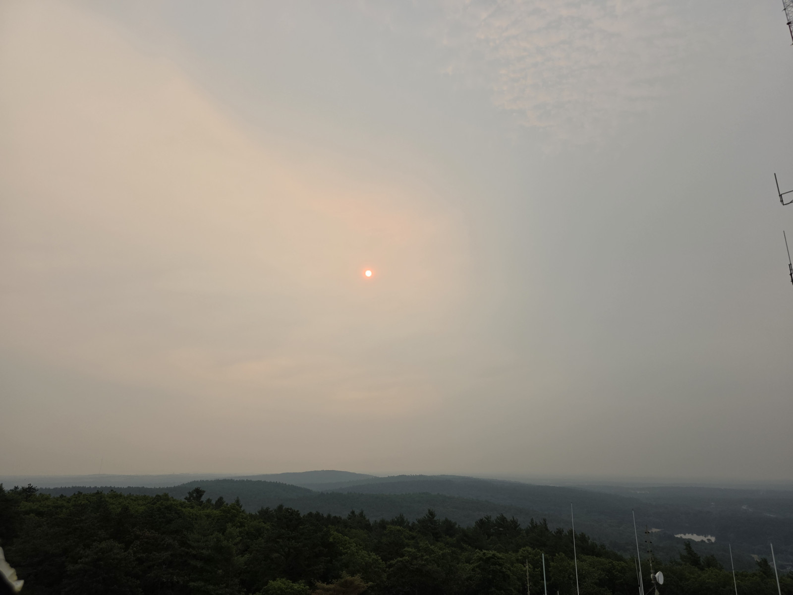 A deep red sun filtered through thick wildfire smoke over the treeline at Blue Hill Observatory on the morning of July 15, 2026