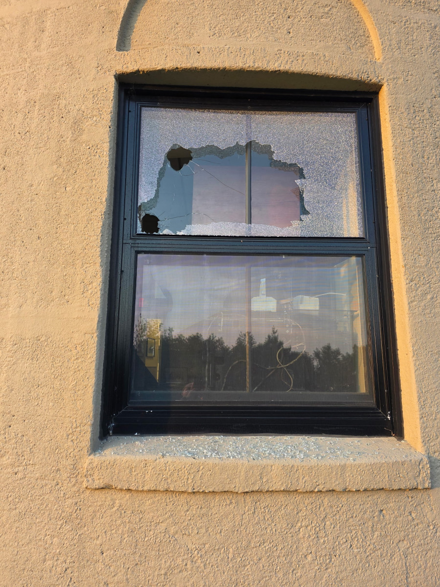 Close-up of shattered glass with a hole punched through a window pane