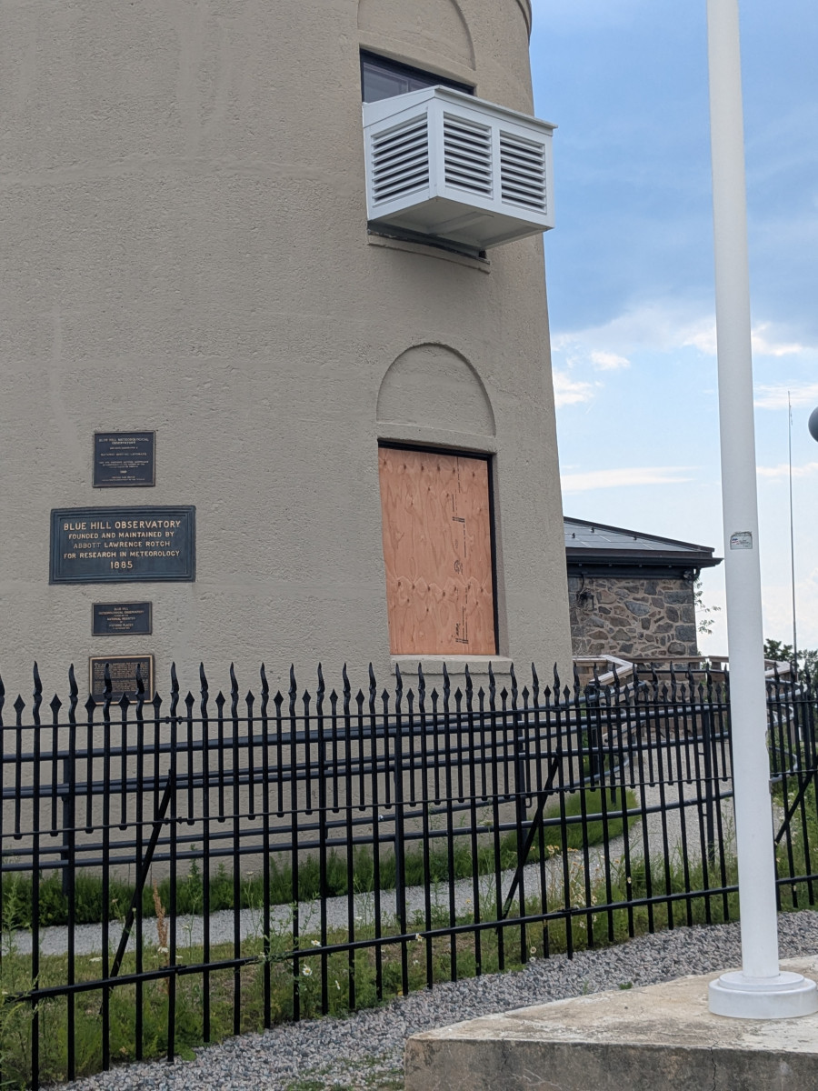 Boarded window on the Observatory's historic stone tower, with landmark plaques visible on the wall